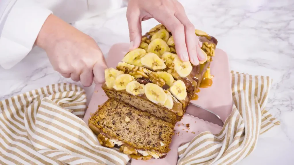 A person greasing a baking pan while preparing banana bread batter in a well-organized kitchen.