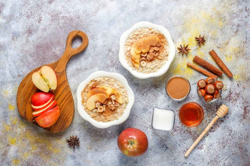 A wholesome apple and cinnamon oatmeal bowl surrounded by fresh apples and natural toppings.